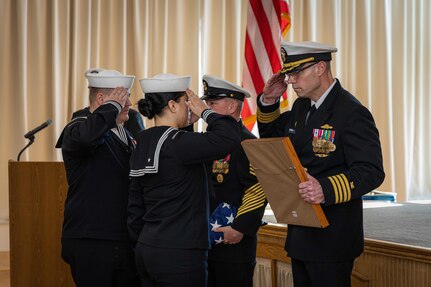 Rear Adm. Dennis Collins, right, Commander, Navy Expeditionary Logistics Support Group, and Fourth Navy Expeditionary Logistics Regiment (NELR) Command Master Chief Stephen Jones, present challenge coins to 4th NELR Sailors during the decommissioning ceremony of 4th NELR at Naval Station Mayport, Florida, Jan. 20, 2023.