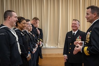 Rear Adm. Dennis Collins, right, Commander, Navy Expeditionary Logistics Support Group, and Fourth Navy Expeditionary Logistics Regiment (NELR) Command Master Chief Stephen Jones, present challenge coins to 4th NELR Sailors during the decommissioning ceremony of 4th NELR at Naval Station Mayport, Florida, Jan. 20, 2023.