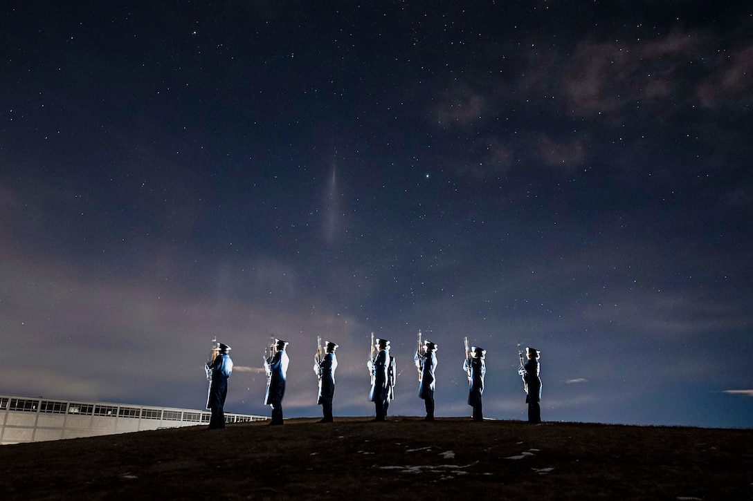 Air Force cadets stand in formation at night.