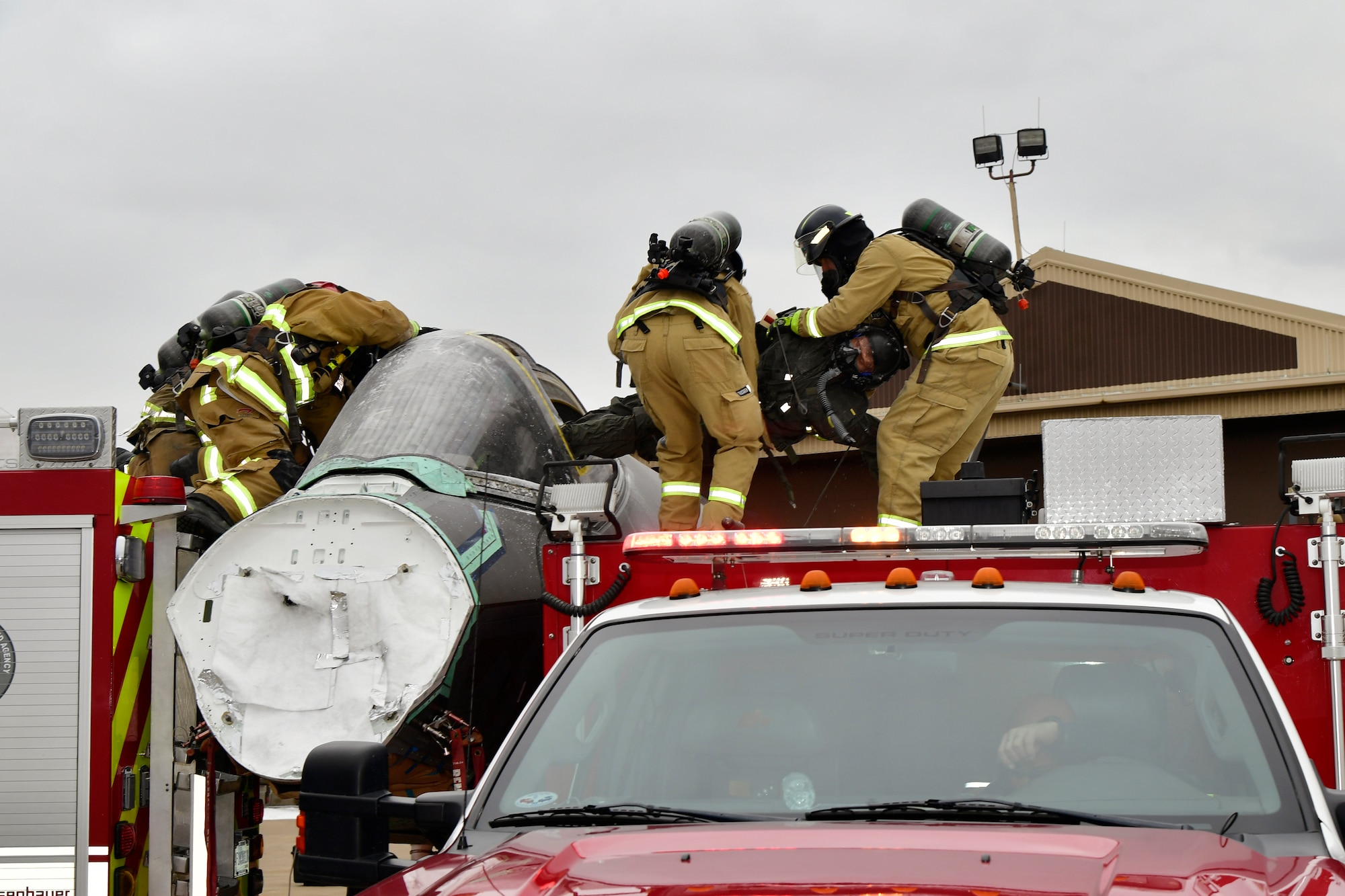 Air Force firefighters use fire trucks to shield aircraft inlets, while practicing emergency aircrew extraction with a dummy Jan. 24, 2023, at Hill Air Force Base, Utah. This was one of several scenarios practiced during an emergency responder working group exercise attended by first responders from across the Air Force to explore emergency engine shutdown and aircrew extraction best practices specific to F-35 aircraft. (U.S. Air Force photo by Todd Cromar)