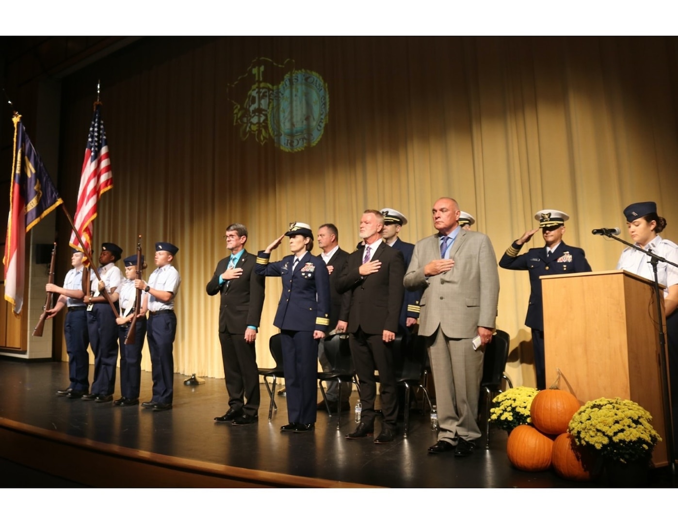 Four cadets from the Topsail High School Coast Guard JROTC color guard present the colors at their Unit Establishment Ceremony at Topsail High School in Hampstead, North Carolina, Oct. 27, 2022. Representative Carson Smith from the North Carolina General Assembly (front row, left) and Rear Admiral Megan Dean, Coast Guard Director of Governmental and Public Affairs (front row, second from left) each delivered remarks during the ceremony. (U.S. Coast Guard photo.)