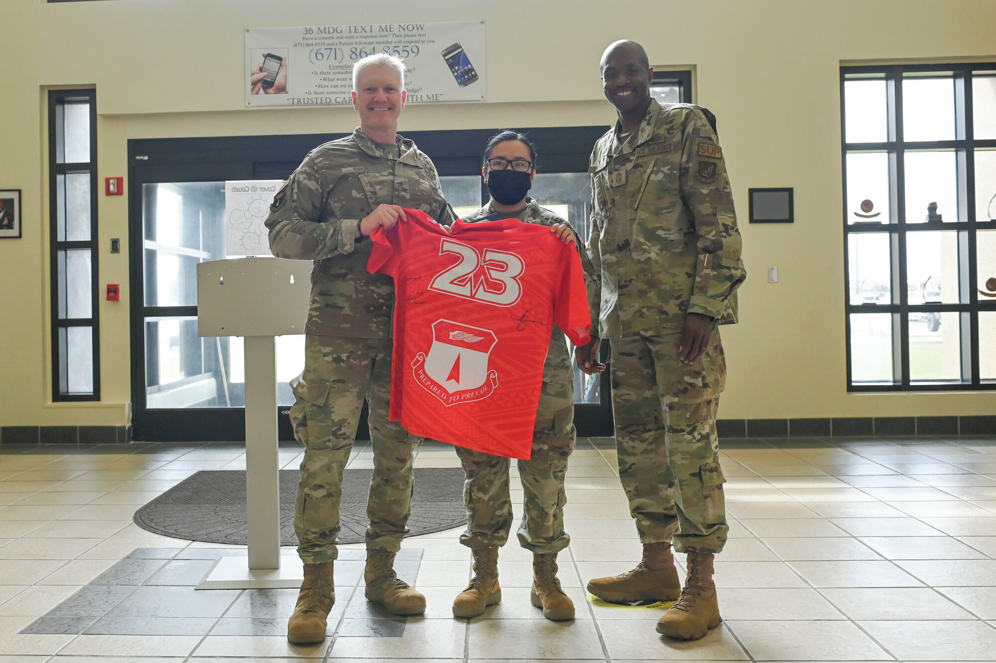 Three people pose with a jersey.