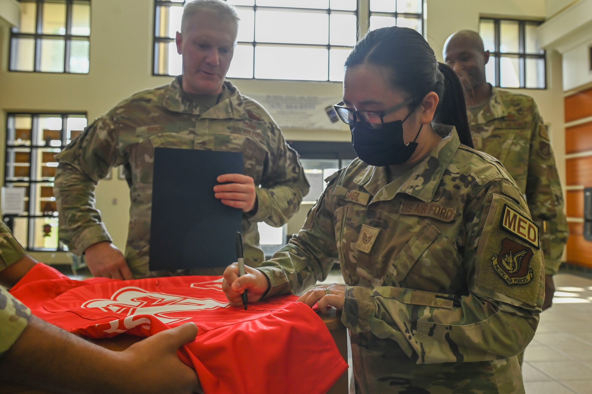 A woman signs a red jersey.