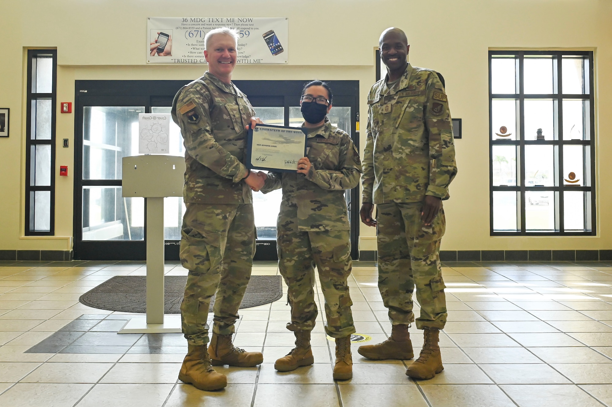 Three people pose with a certificate