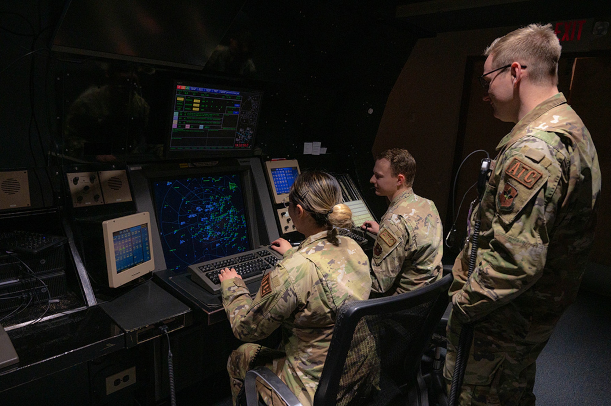 U.S. Air Force Senior Airmen Kristen McQueen (left), Nicholas Anderson (center), and Tyler Turnbull (right), 56th Operation Support Squadron radar approach control trainers, monitor flight paths of aircraft, Jan. 27, 2023, at Luke Air Force Base, Arizona.