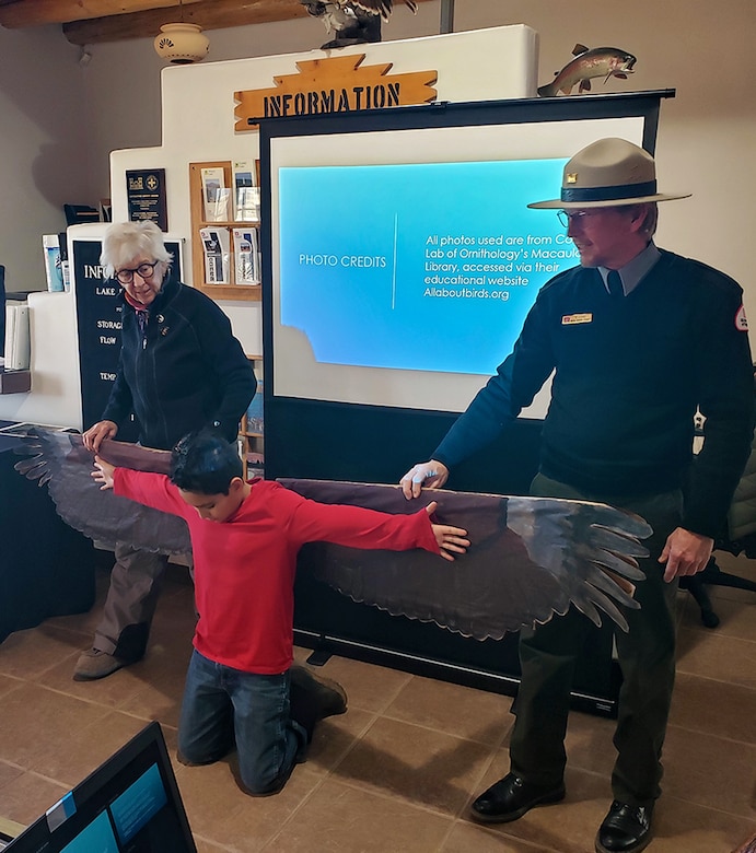 Abiquiu Lake park ranger Brady Dunne (right) and biologist Kathrine Eagleson demonstrate the size of an eagle’s wingspan with help from a volunteer, in a presentation to volunteers before the annual Midwinter Bald Eagle Watch at the lake, Jan. 7, 2023.