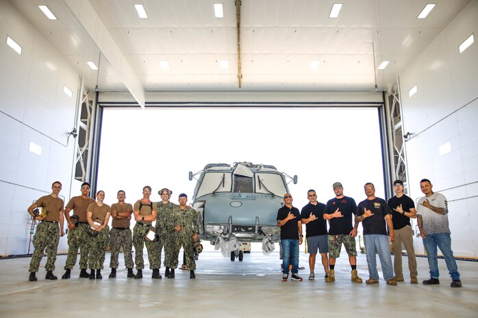 U.S. Navy Sailors with Helicopter Maritime Strike Squadron 37 pose for a group photo with paint hangar staff, Marine Corps Base Hawaii, Jan. 19, 2023. The new paint hangar allows for aircraft to be stripped, checked for damage, repaired, and repainted. The UH-60 shown will be the first aircraft to ever make use of the hangar. (U.S. Marine Corps photo by Cpl. Brandon Aultman)