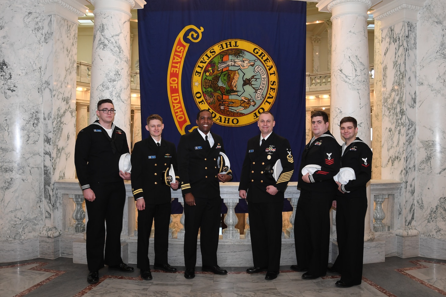 Crewmembers from the future USS Idaho (SSN 799) pose in front of the Idaho state flag during a tour of the capital building in Boise, Idaho, Jan. 25.