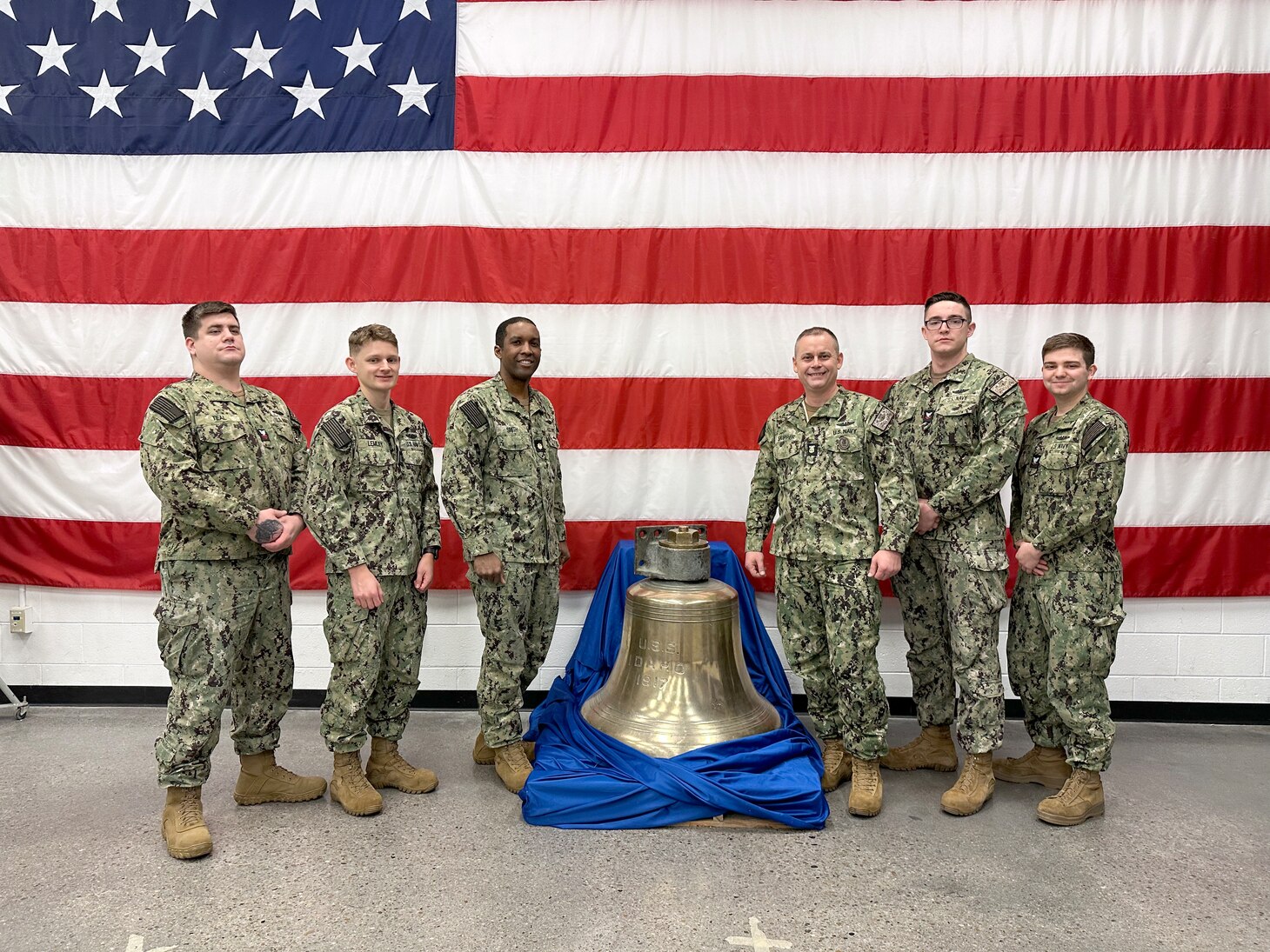 Crewmembers of the future USS Idaho (SSN 799) pose in front of a ship’s bell from the WWII Battleship (BB) 42 USS Idaho during a tour of the Navy Reserve Center in Boise, Idaho, Jan. 26.