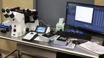 Picture of microscope on table with computer monitor