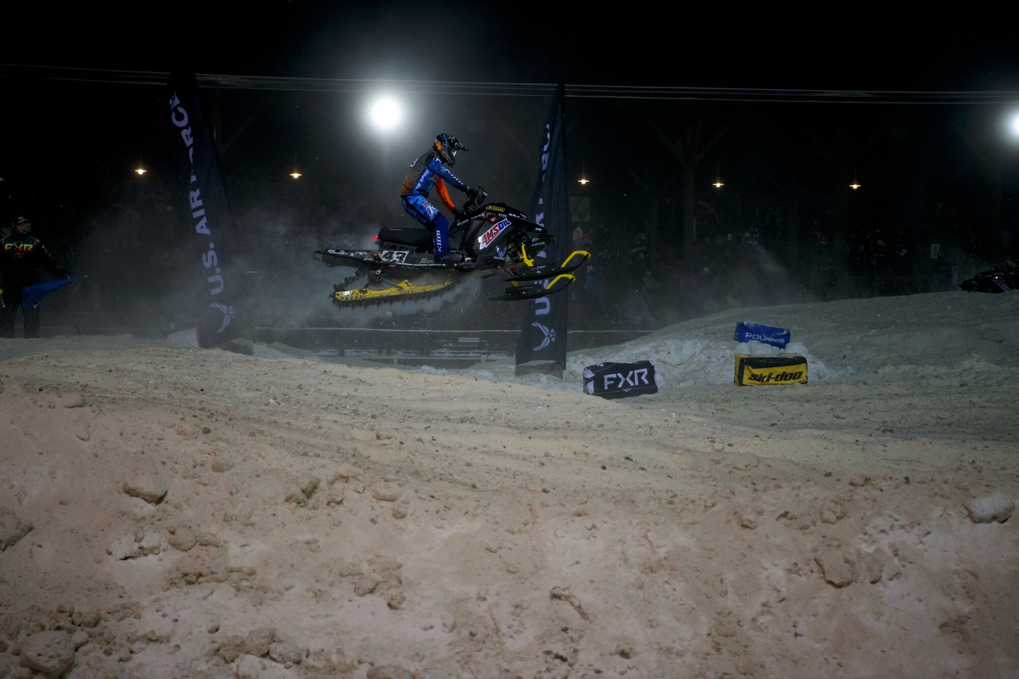 A snowmobile rider jumps over a snow hill
