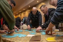 U.S. Marines and Sailors from across III Marine Expeditionary Force coordinate with their teammates to solve a puzzle during a Scrum for Warfighters teambuilding seminar at Camp Kinser, Okinawa, Japan, Jan. 9, 2023. Scrum for Warfighters gives senior leaders an opportunity to share new ways to adapt and overcome to continuously changing environments and sharpen their problem-solving skills together. (U.S. Marine Corps photo by Lance Cpl. Sydni Jessee)