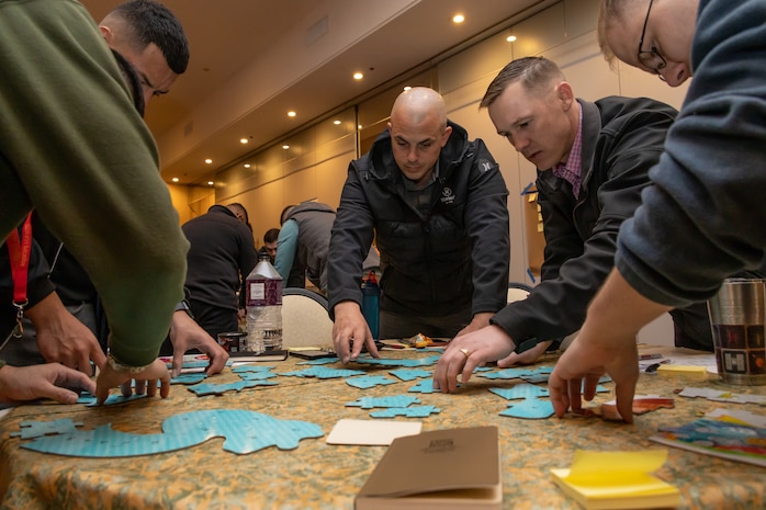 U.S. Marines and Sailors from across III Marine Expeditionary Force coordinate with their teammates to solve a puzzle during a Scrum for Warfighters teambuilding seminar at Camp Kinser, Okinawa, Japan, Jan. 9, 2023. Scrum for Warfighters gives senior leaders an opportunity to share new ways to adapt and overcome to continuously changing environments and sharpen their problem-solving skills together. (U.S. Marine Corps photo by Lance Cpl. Sydni Jessee)
