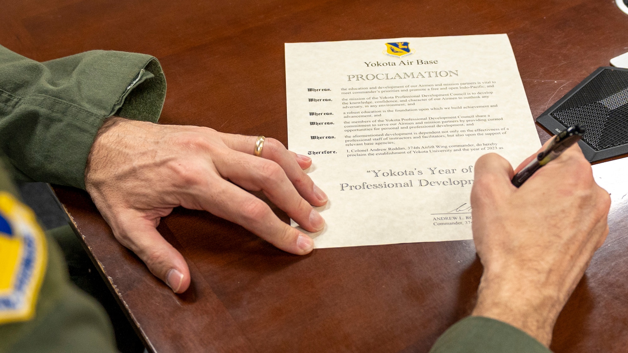 A close up of a hand signing the proclamation