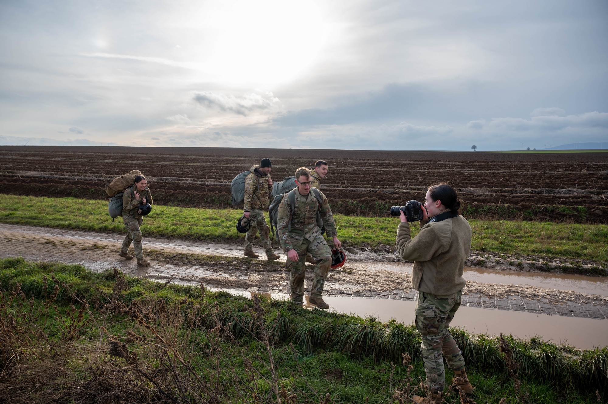 U.S. Air Force Airman 1st Class Kaitlyn Oiler, 86th Airlift Wing public affairs apprentice, right, takes a photograph of Airmen from the 435th Security Forces Squadron, including her husband, Staff Sgt. Matthew Oiler, 435th Contingency Response Group team chief, after a static line jump at Alzey Drop Zone in Ober-Flörsheim, Germany, Jan. 20, 2023. Airman 1st Class Oiler said she was proud of her husband because he was successful on each jump during training and earned his wings. (U.S. Air Force photo by Staff Sgt. Branden Rae)