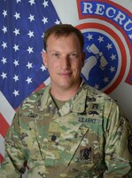 Male Soldier posed in front of two flags.