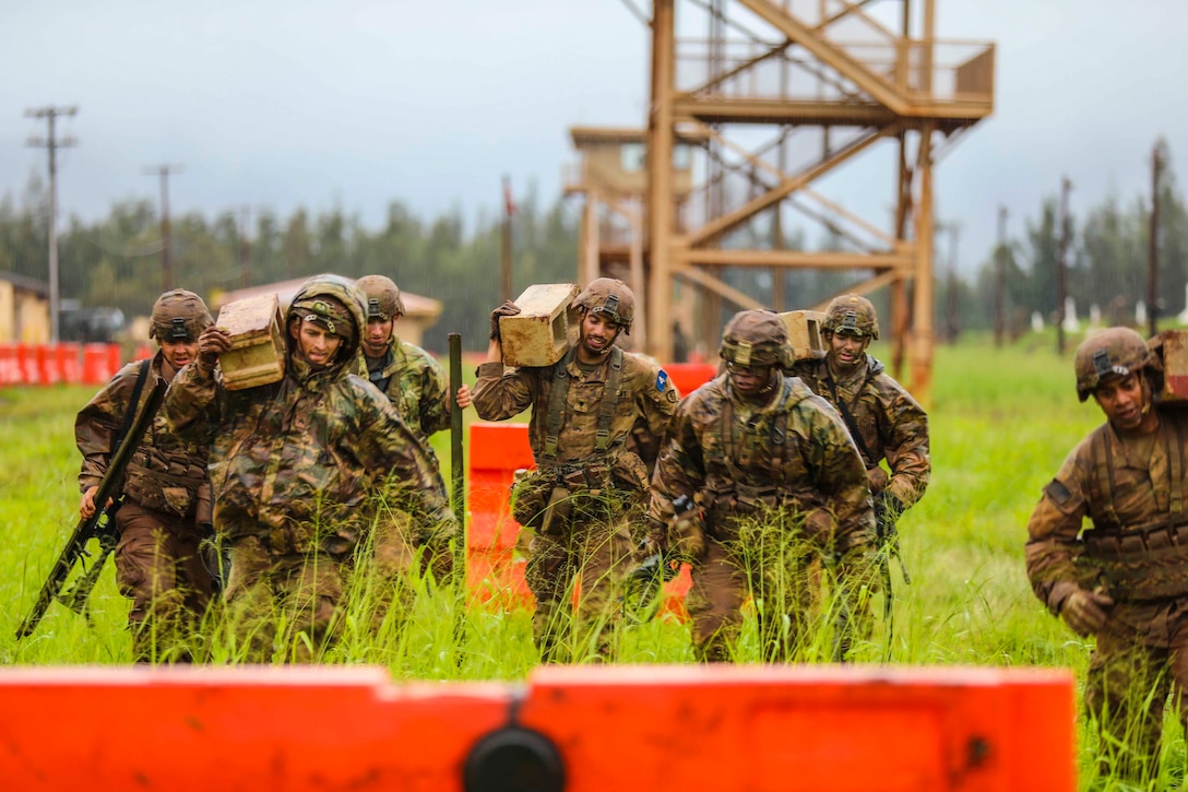 Soldiers walk in a group; some carrying cinder blocks.