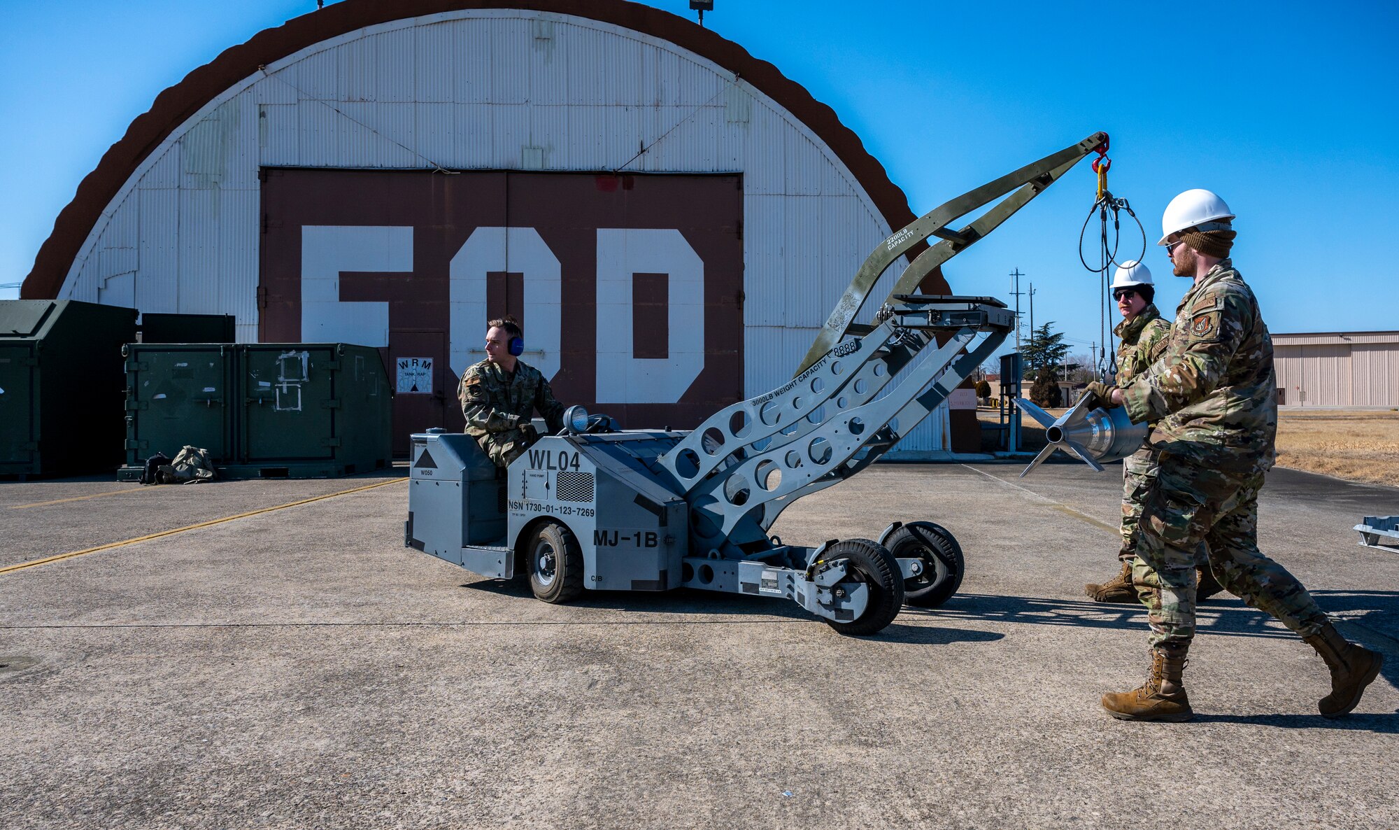 U.S. Air Force Staff Sgt. Joshua Sandy, 51st Munitions Squadron (MUNS) munitions inspector, and Staff Sgt. Zachary Johnson, 51st MUNS precision missiles crew chief, guide a MJ-1C weapons loader driven by Staff Sgt. Christian Mathes, 51st MUNS maintenance supervisor, during a training event at Daegu Air Base, Republic of Korea, Jan. 30, 2023.