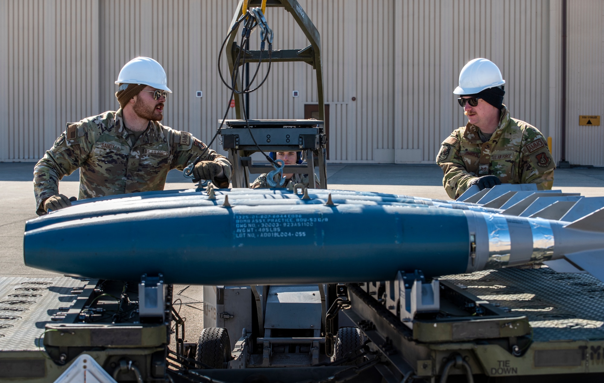 U.S. Air Force Staff Sgt. Joshua Sandy, 51st Munitions Squadron (MUNS) munitions inspector, and Staff Sgt. Zachary Johnson, 51st MUNS precision missiles crew chief, guide a MJ-1C weapons loader driven by Staff Sgt. Christian Mathes, 51st MUNS maintenance supervisor, during a training event at Daegu Air Base, Republic of Korea, Jan. 30, 2023.