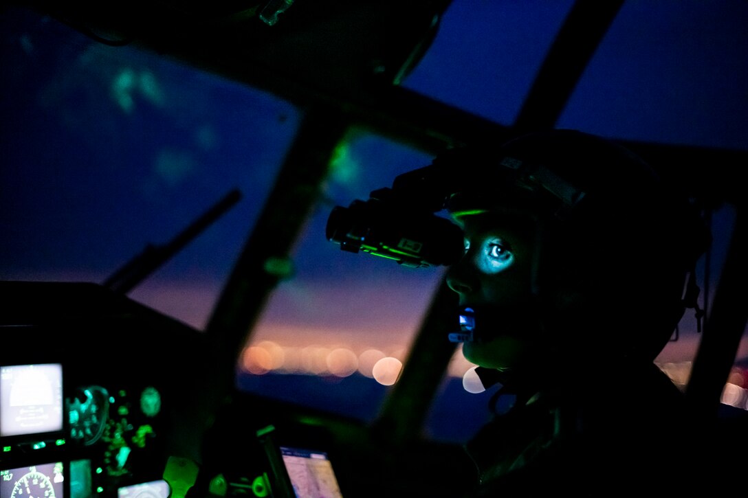 Close up of an airman inside the cockpit of a military aircraft at dusk.