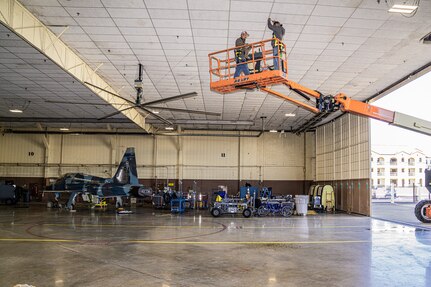 Male workers on crane in aircraft hanger