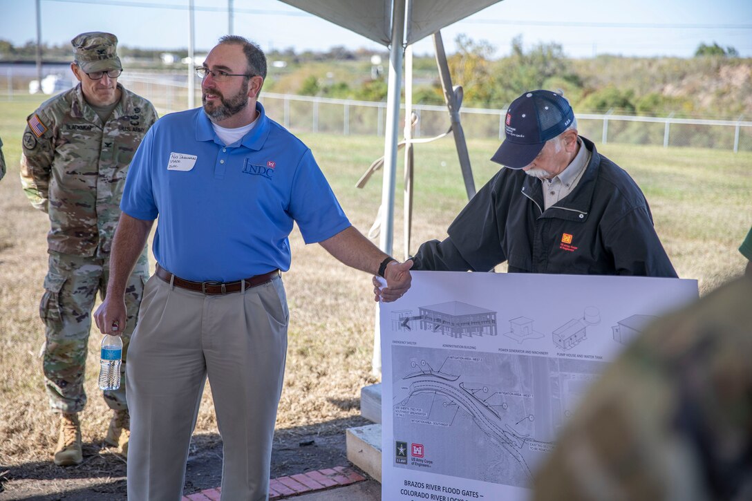 one person speaks while pointing to a project design poster