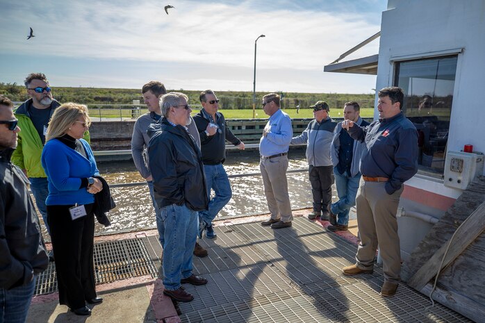one person speaks with several people on the edge of a river