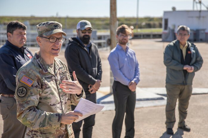 one person in military uniform speaks with several people in the background