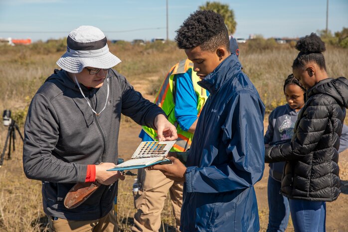 an adult uses a guide binder to explain soil identification to a child