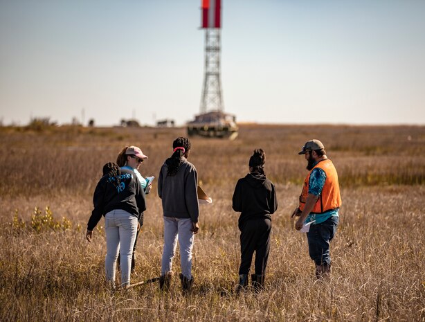 adults and children stand in a grassy wetland