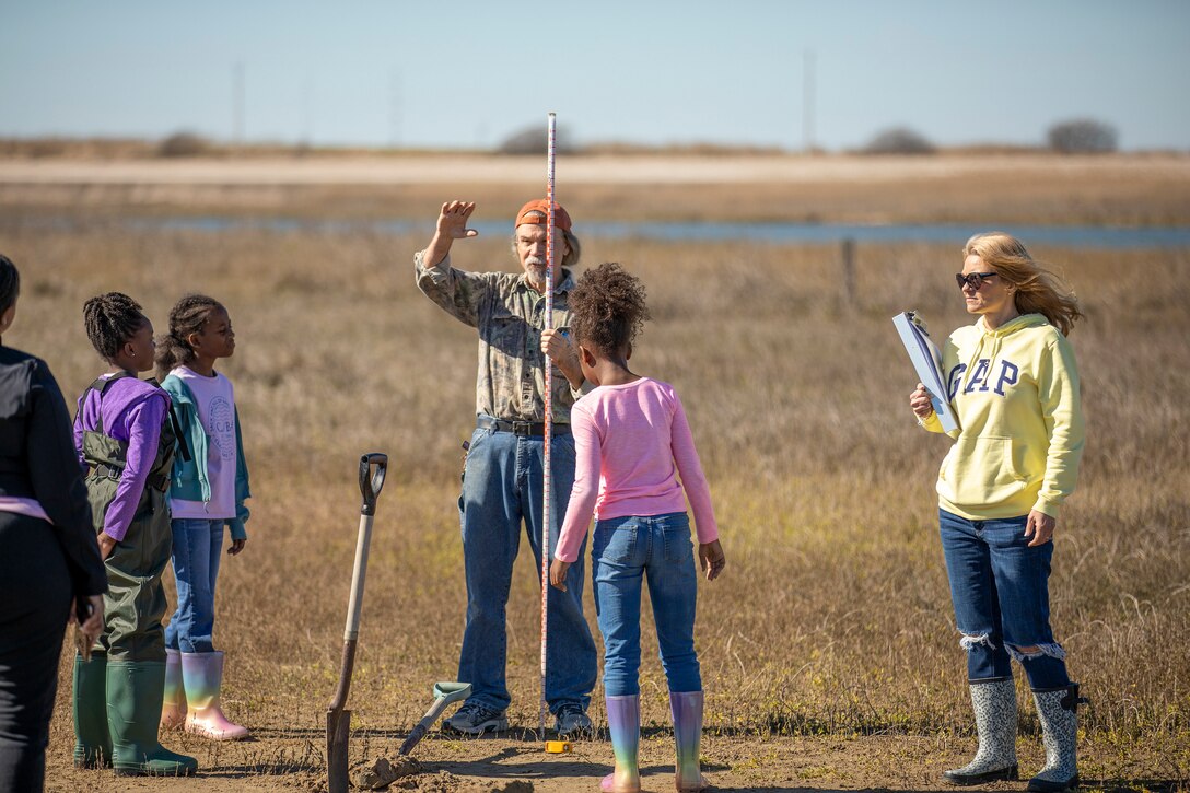 an adult explains how to survey a wetland to other adults and children