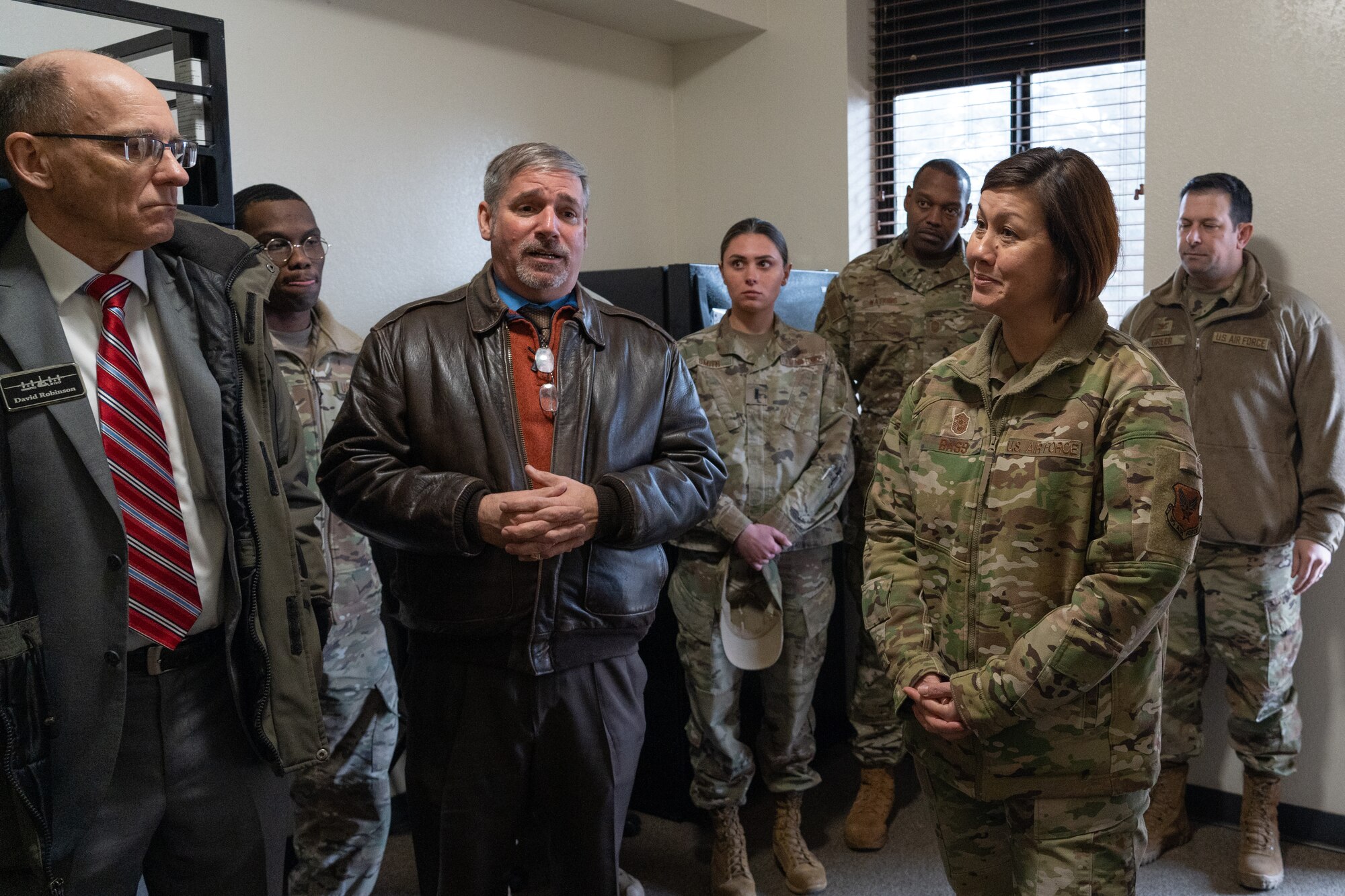 Civilians and Air Force members stand in a room.