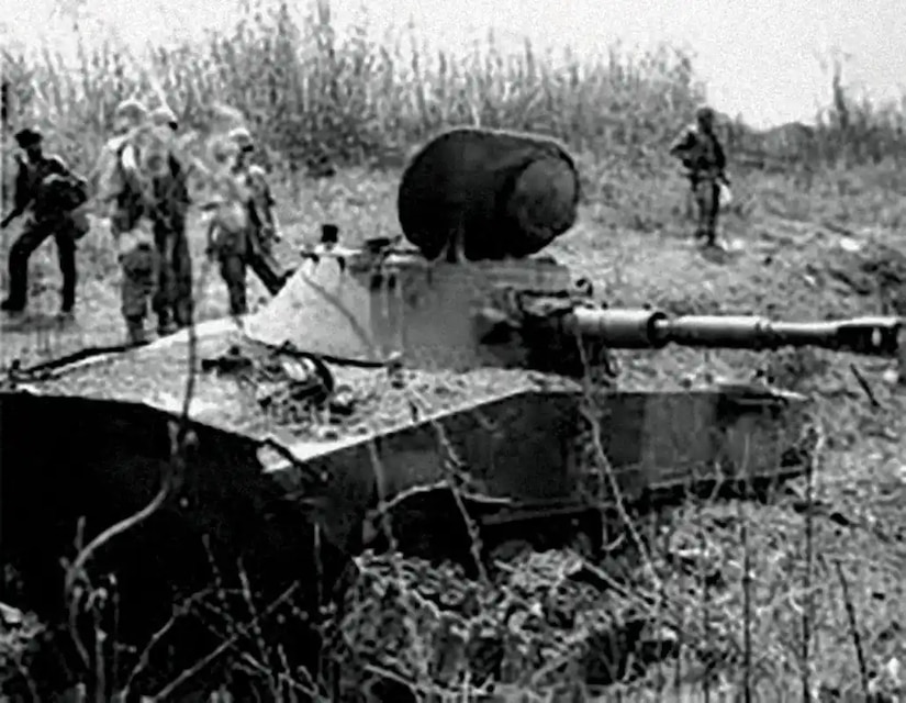 Men gawk at a destroyed tank.