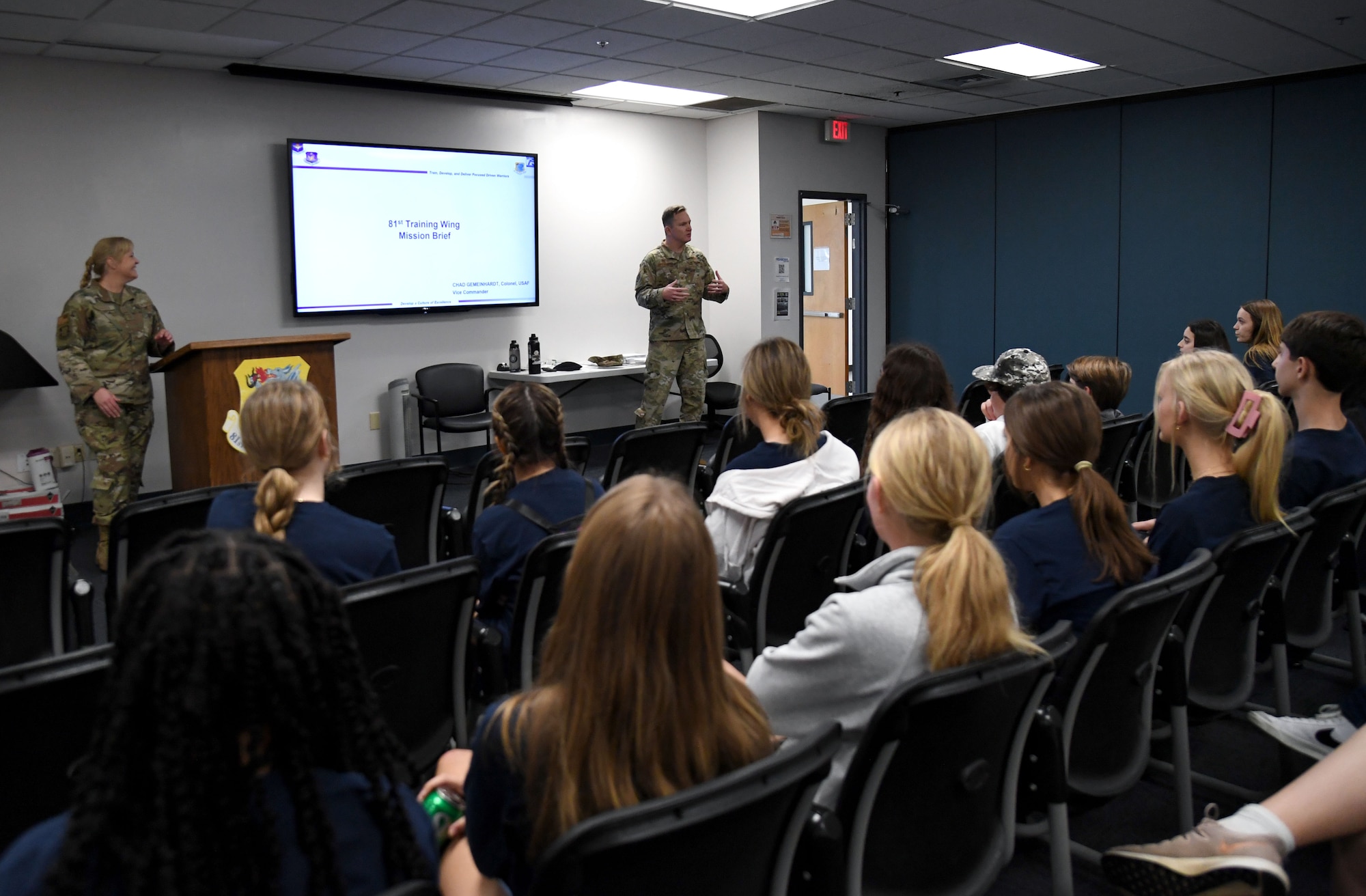 U.S. Air Force Col. Chad Gemeinhardt, 81st Training Wing vice commander, and Chief Master Sgt. Sarah Esparza, 81st TRW command chief, deliver the 81st TRW mission brief to members of the Biloxi Chamber of Commerce Junior Leadership Program inside the Levitow Training Support Facility at Keesler Air Force Base, Mississippi, Jan. 31, 2023.
