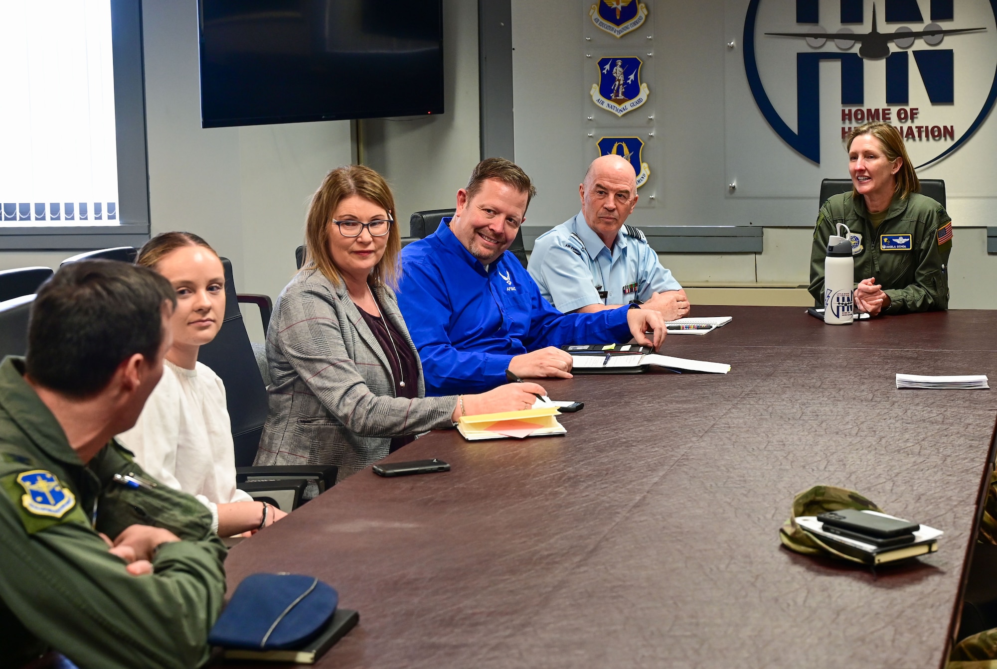 Men and women sit down around a table and have a meeting.