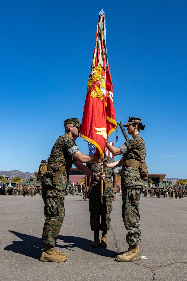 U.S. Marine Corps Lt. Col. Carrie Stocker, right, the off-going commander of 1st Transportation Battalion, Combat Logistics Regiment 1, 1st Marine Logistics Group, passes the unit colors to Lt. Col. Andrew Harkins