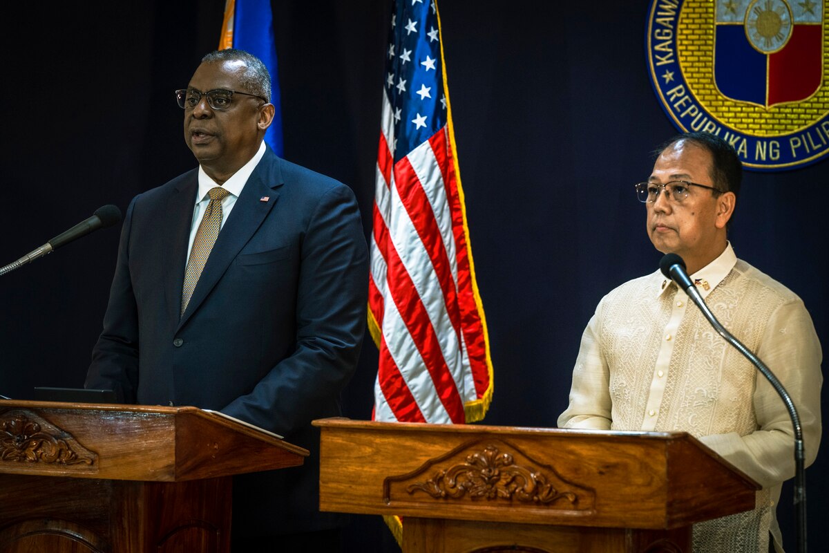 Two men stand next to each other on a stage and answer questions.