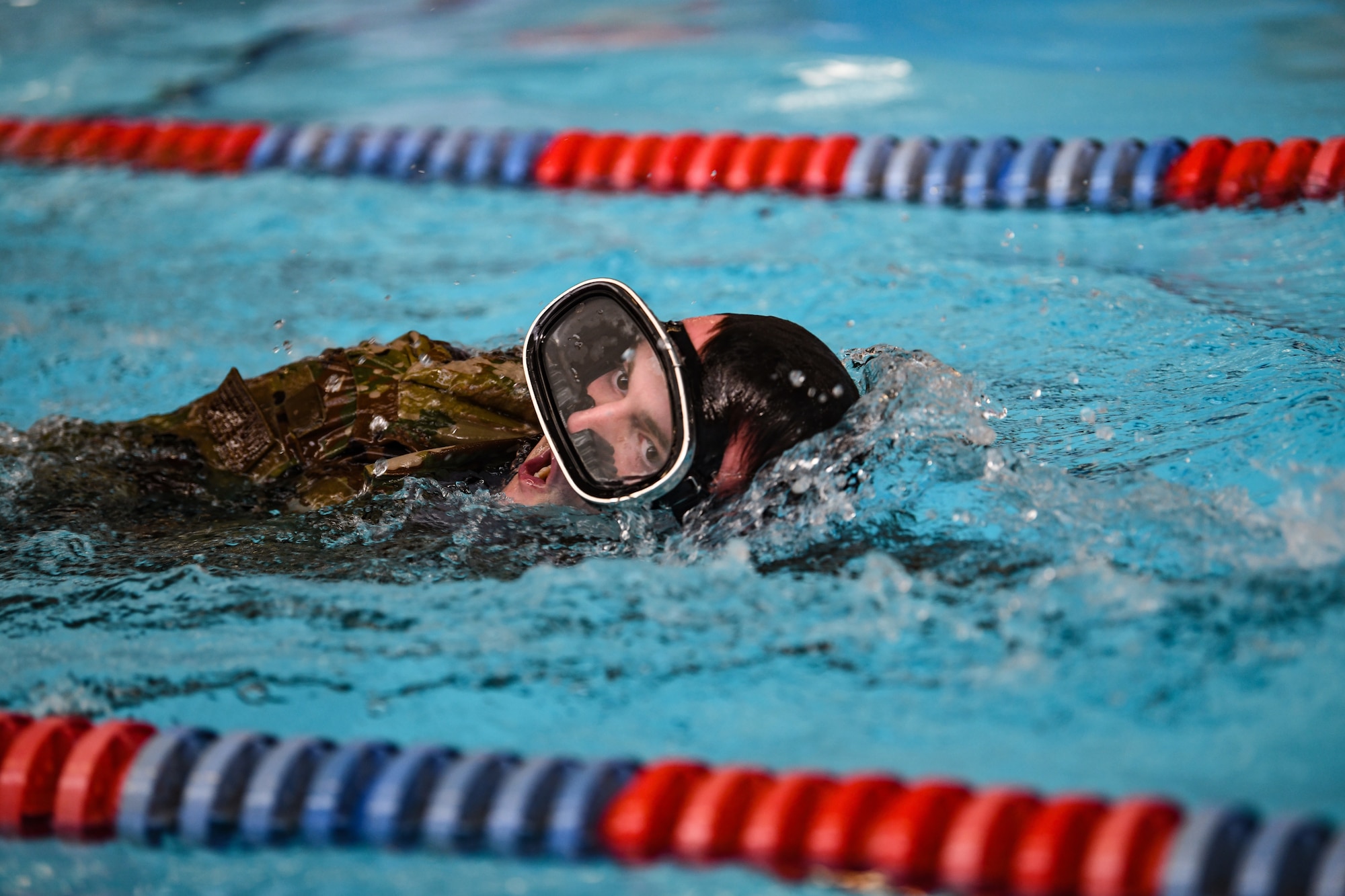 An airman takes a breath as he swims in a pool.