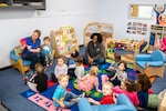 A staff member from the Child Development Center reads a book to children at RAF Alconbury, England, Feb. 2, 2023. The RAFA CDC provides quality child development and services to children and families from all four branches of the Department of Defense. (U.S. Air Force photo by Staff Sgt. Eugene Oliver)