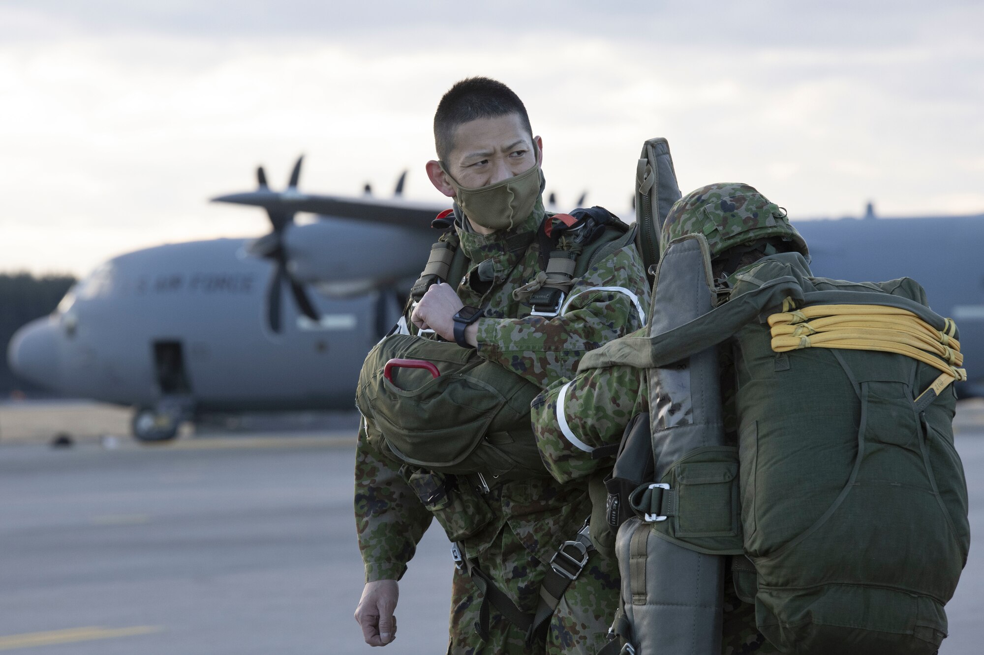 Two Japanese soldiers check their parachutes on a flight line