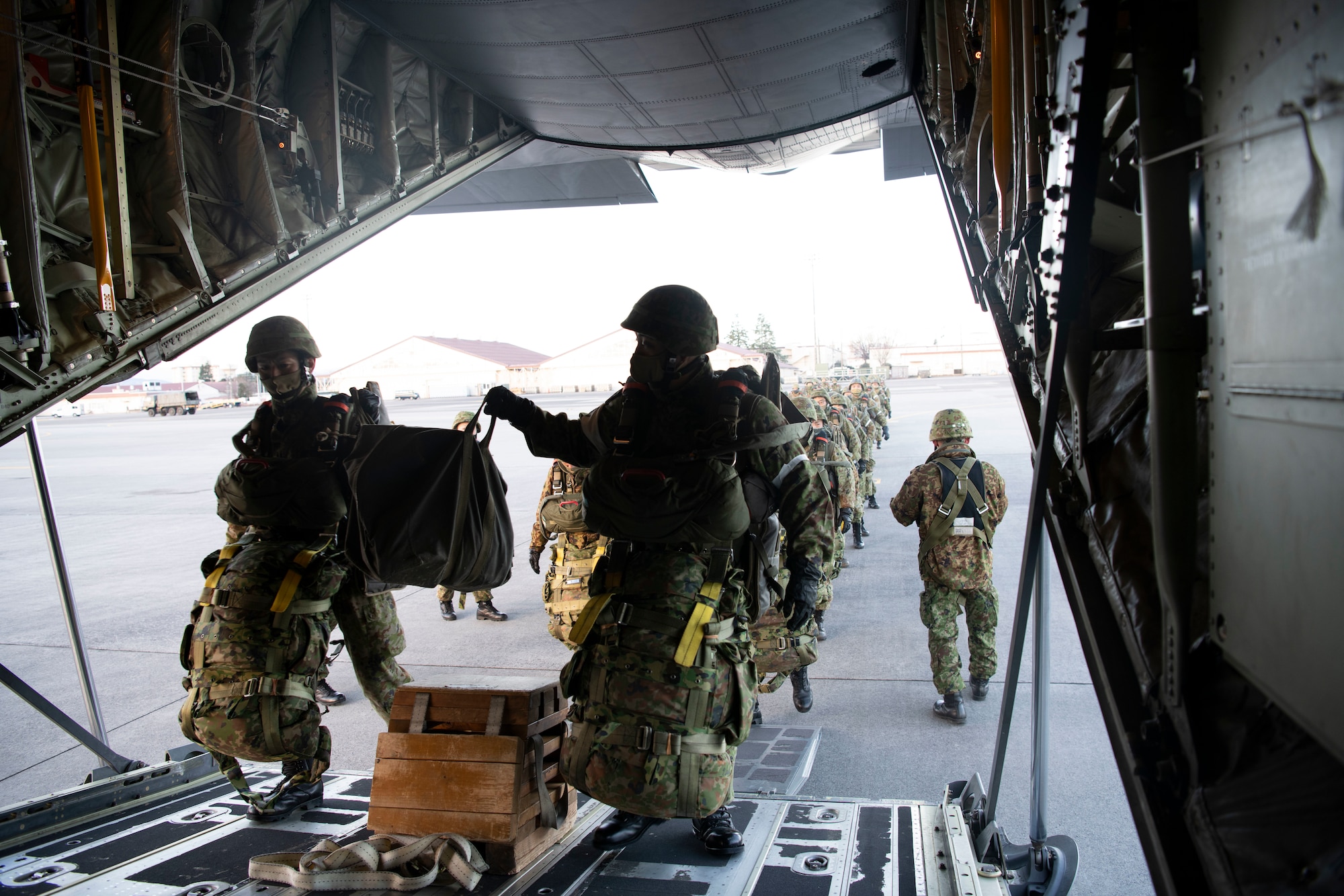 Japanese soldiers march onto a cargo plane via the rear loading ramp