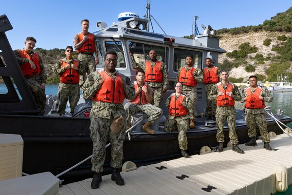 The Port Operations Team of Naval Support Activity (NSA) Souda Bay is pictured in front of one of their Port Ops boats. The team supports U.S., Allied, Coalition, and Partner nation forces operating in the U.S. Sixth Fleet through port services and oil spill prevention and response for visiting assets.
