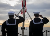Seaman Dylan Duce, left, and Airman Evan Rowe, both assigned to the Nimitz-class aircraft carrier USS George H.W. Bush (CVN 77), salute the American flag, as the ship along with the embarked staff of Carrier Strike Group (CSG) 10, arrives in Piraeus, Greece, for a scheduled port visit, Feb. 3, 2023.