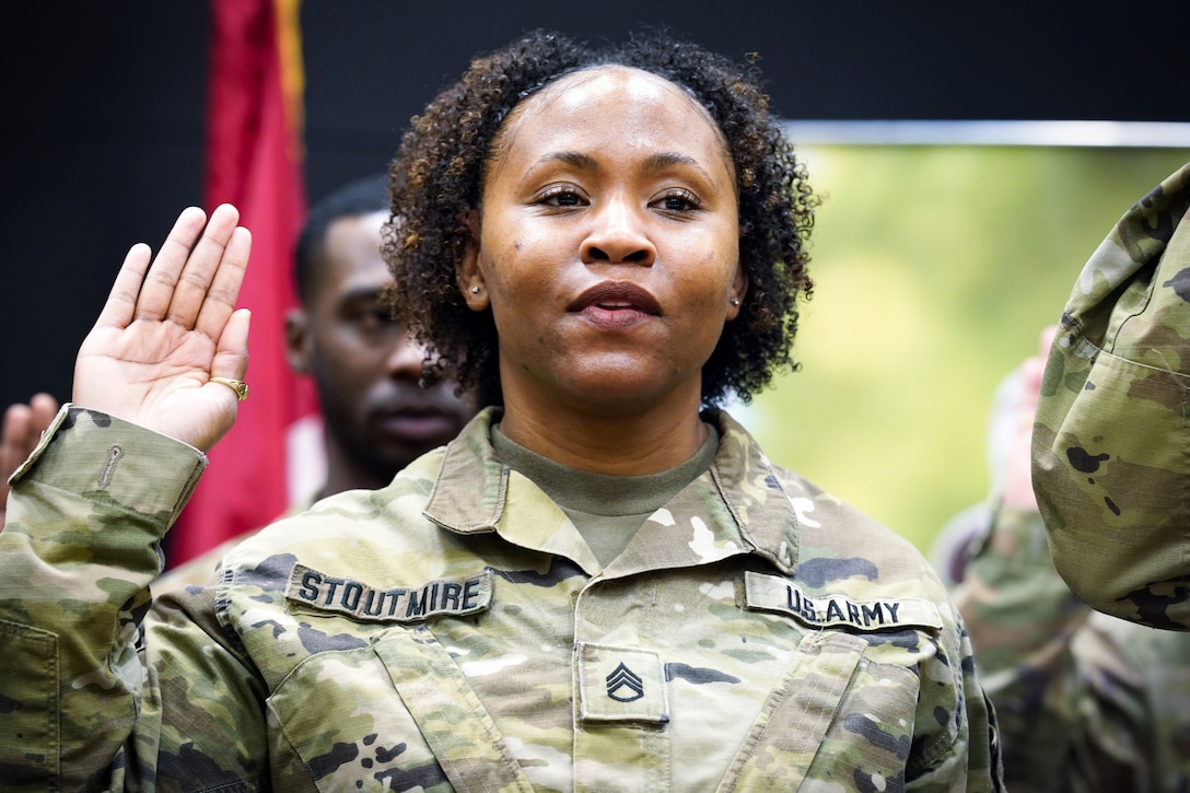 A soldier raises her hand during a reenlistment ceremony.