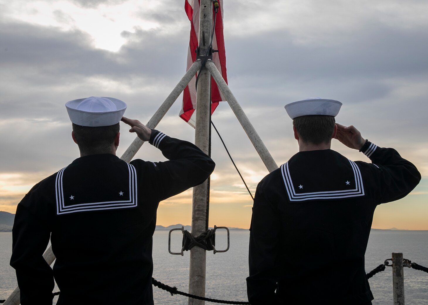 Seaman Dylan Duce, left, and Airman Evan Rowe, both assigned to the Nimitz-class aircraft carrier USS George H.W. Bush (CVN 77), salute the American flag, as the ship along with the embarked staff of Carrier Strike Group (CSG) 10, arrives in Piraeus, Greece, for a scheduled port visit, Feb. 3, 2023.