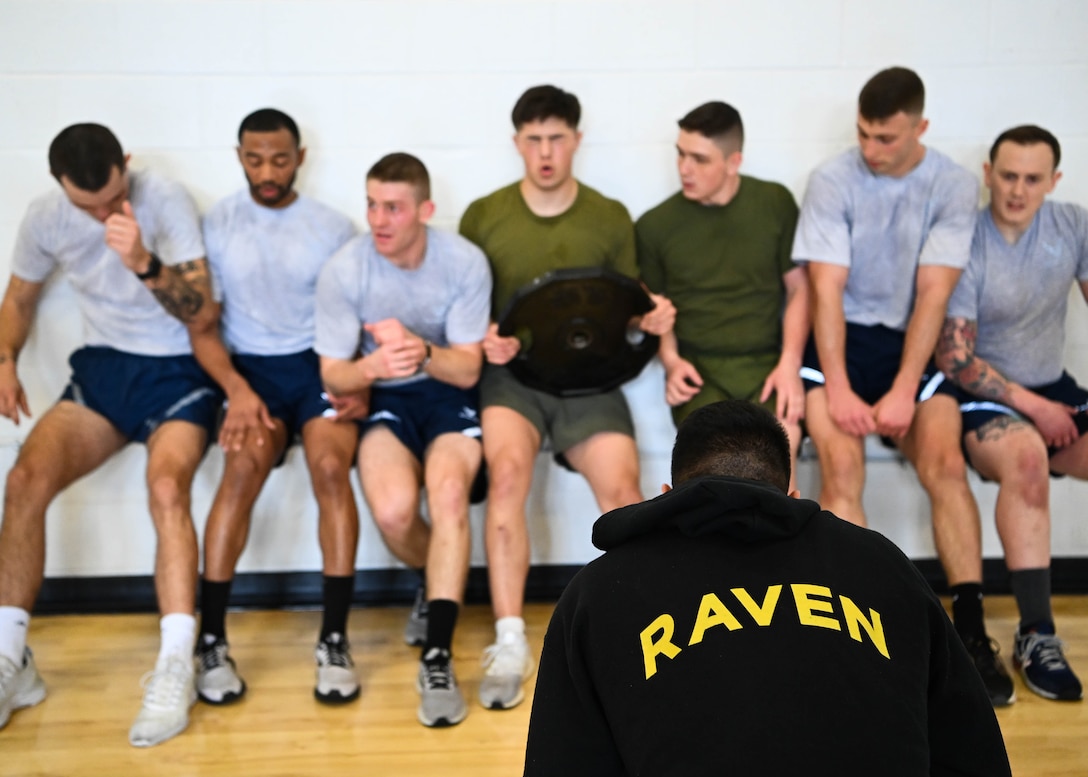 Military members in physical training uniforms perform exercises.