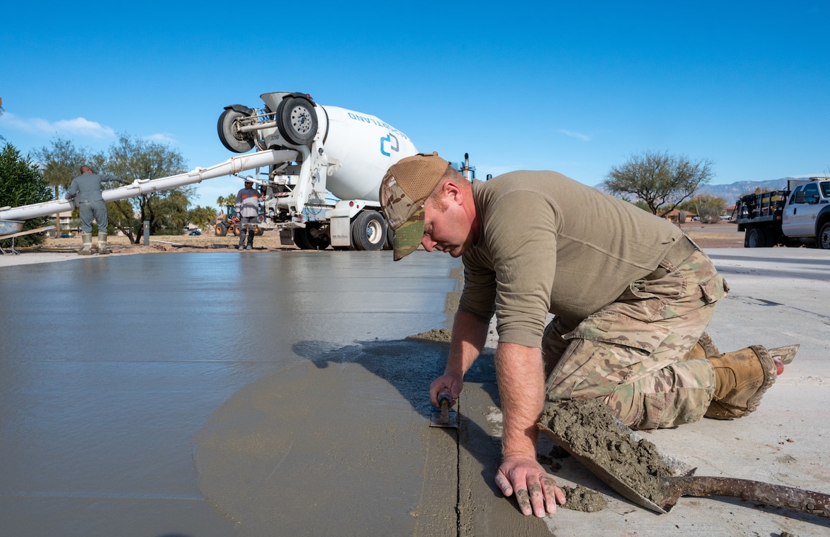 A photo of a man leveling the edge of poured concrete.