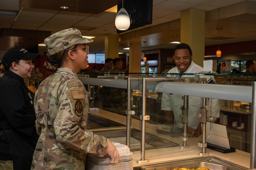 U.S. Airmen assigned to the 5th Force Support Squadron receive compliments for their customer service and cooking during a lunch service from a member of the Hennessy Award committee at Minot Air Force Base, North Dakota, Jan. 31, 2023. Minot AFB was one of two finalists for the 2023 Hennessy Award. (U.S. Air Force photo by Airman 1st Class Alexander Nottingham)