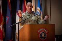 a man wearing u.s. army uniform stands behind a podium.