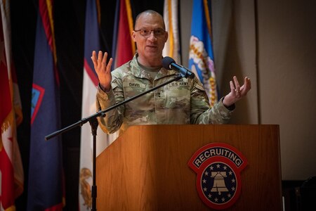 a man wearing u.s. army uniform stands behind a podium.
